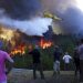 foto: FILE - Villagers watch a firefighting plane drop water to stop a raging forest fire from reaching their homes in Chao de Codes, central Portugal, Aug. 2017.