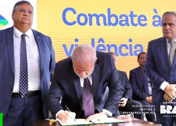 O ministro Flávio Dino de prontidão enquanto o presidente Lula assina novo decreto de armas ambos sendo observados pelo secretário Tadeu Alencar. Foto: Reprodução